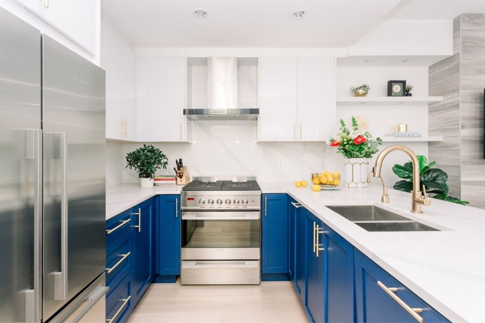 Bright blue kitchen cabinets in white kitchen with white stone backsplash